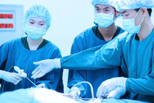 Three surgeons operating in face masks and scrubs