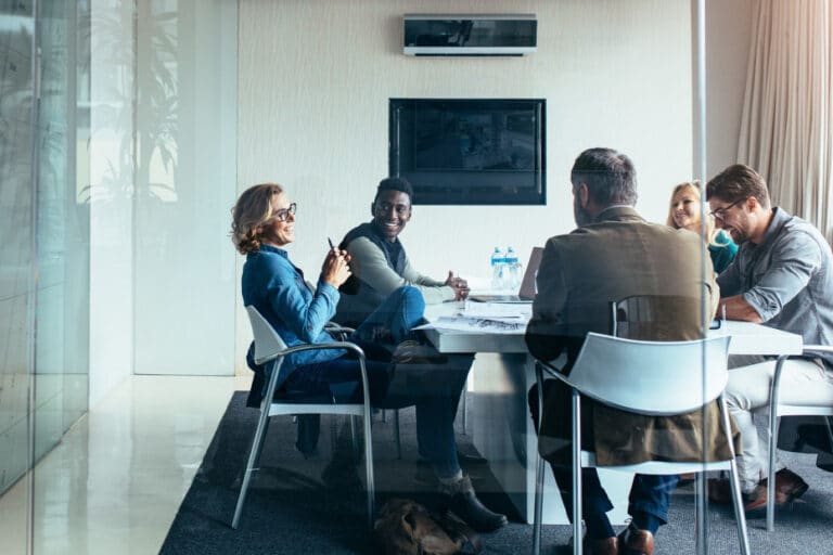 Five smiling people in conference room working on supply chain partnership