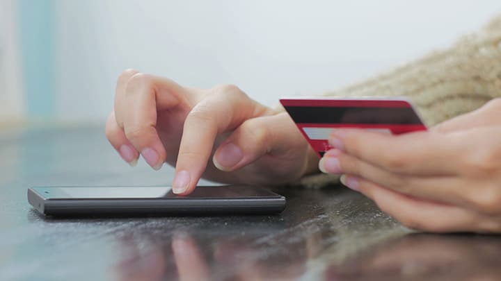 Woman's hands entering credit card number into cell phone