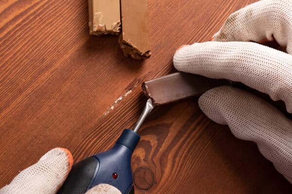 Technician performing in-home furniture repair for scratch on wood